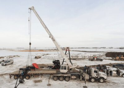 A crane lifts a large wooden beam onto a truck, showcasing heavy machinery in action at a construction site